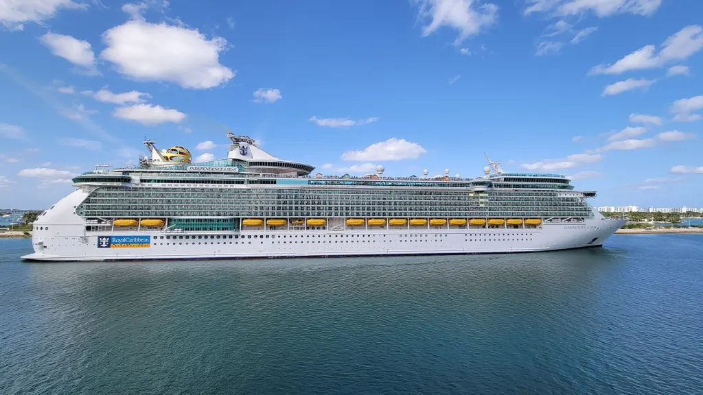The white Royal Caribbean cruise ship Independence of the Seas sailing past PortMiami under a blue sky with scattered clouds