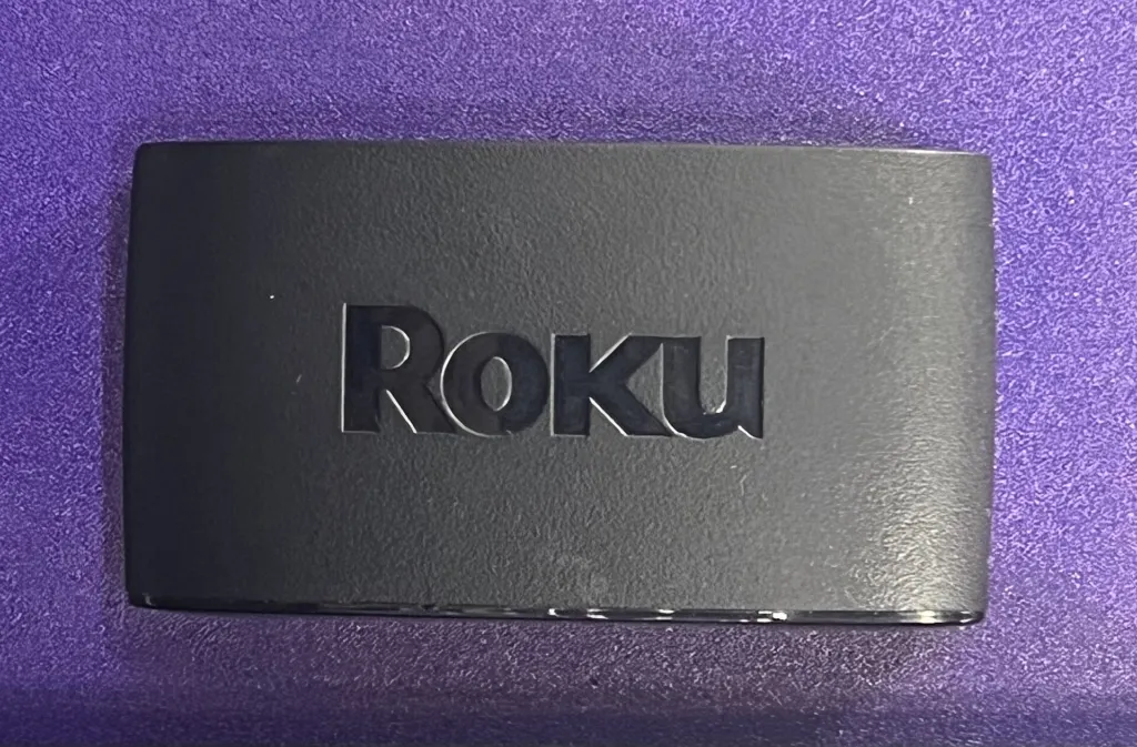 A small black Roku Express streaming player photographed on a flat surface