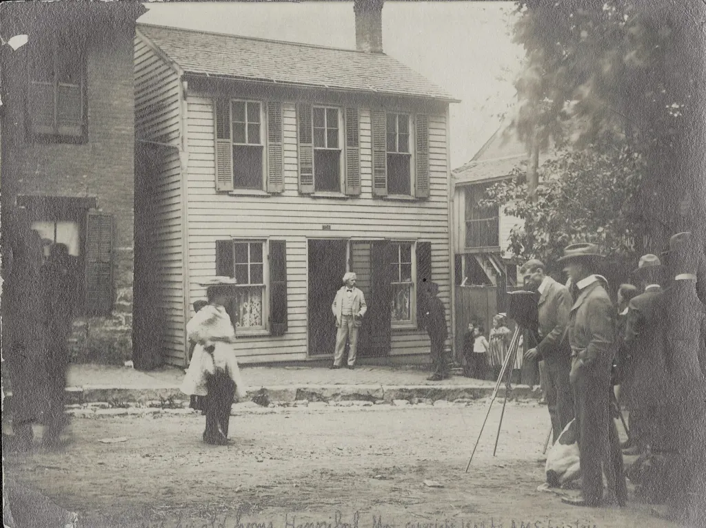 Mark Twain in a white suit standing in the doorway of his boyhood home in Hannibal, Missouri, on May 12, 1902