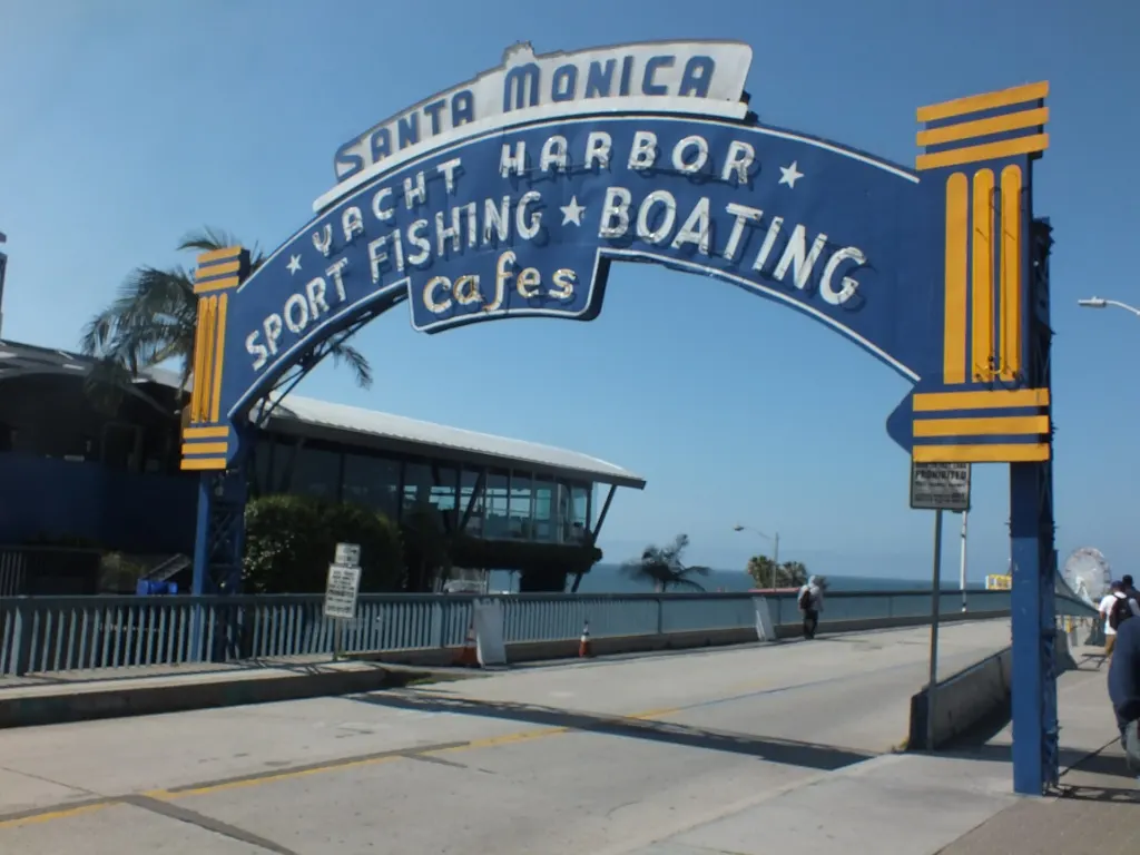 The blue arched Santa Monica Yacht Harbor sign over the entrance to the Santa Monica Pier in California, photographed in April 2024