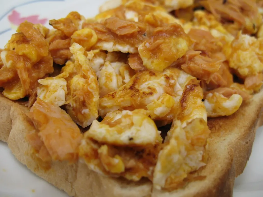 Scrambled eggs mixed with flaked tuna served on slices of toast