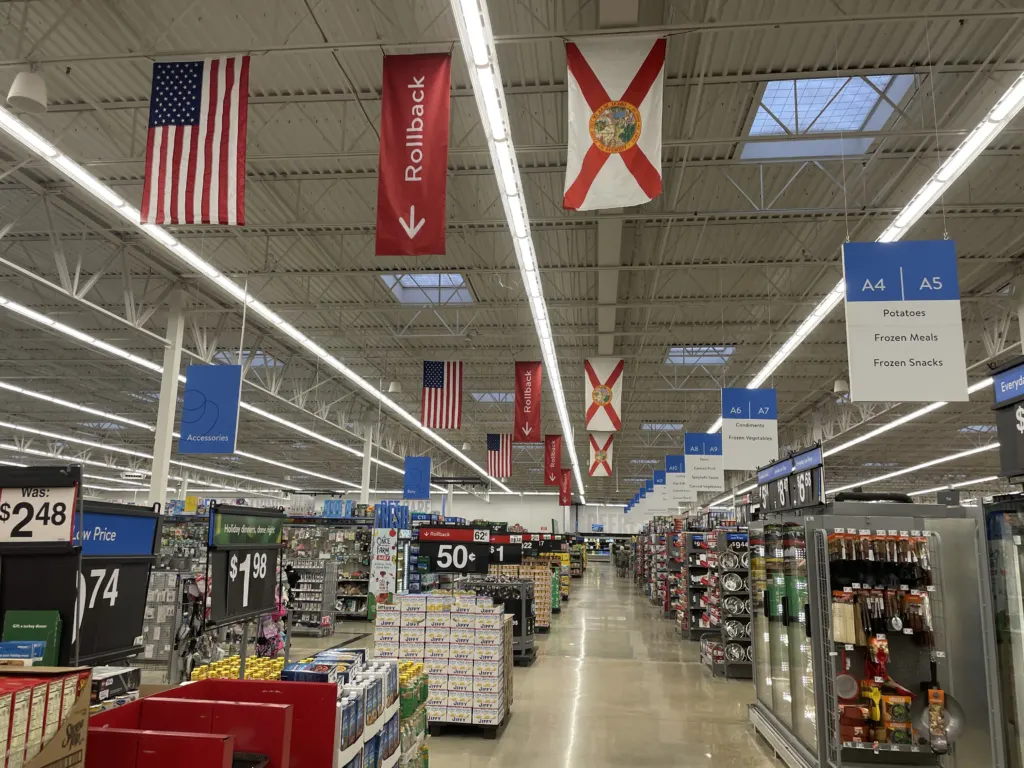 Shopping aisles and overhead department signs inside the Walmart Supercenter on Thomasville Road in Tallahassee, Florida