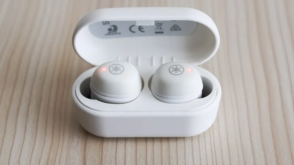 A pair of small true wireless earbuds photographed close up on a table