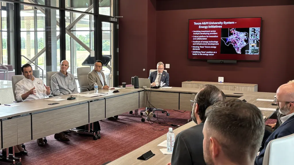 Texas A&M University System officials brief visitors around a conference table, with a screen showing a map of Texas energy initiatives