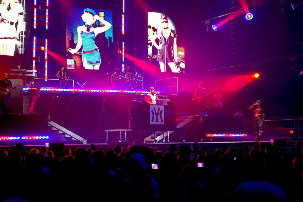 Lil Wayne performs on an arena stage lit in pink and blue, with large video screens behind him and a crowd in the foreground, at General Motors Place in Vancouver in January 2009