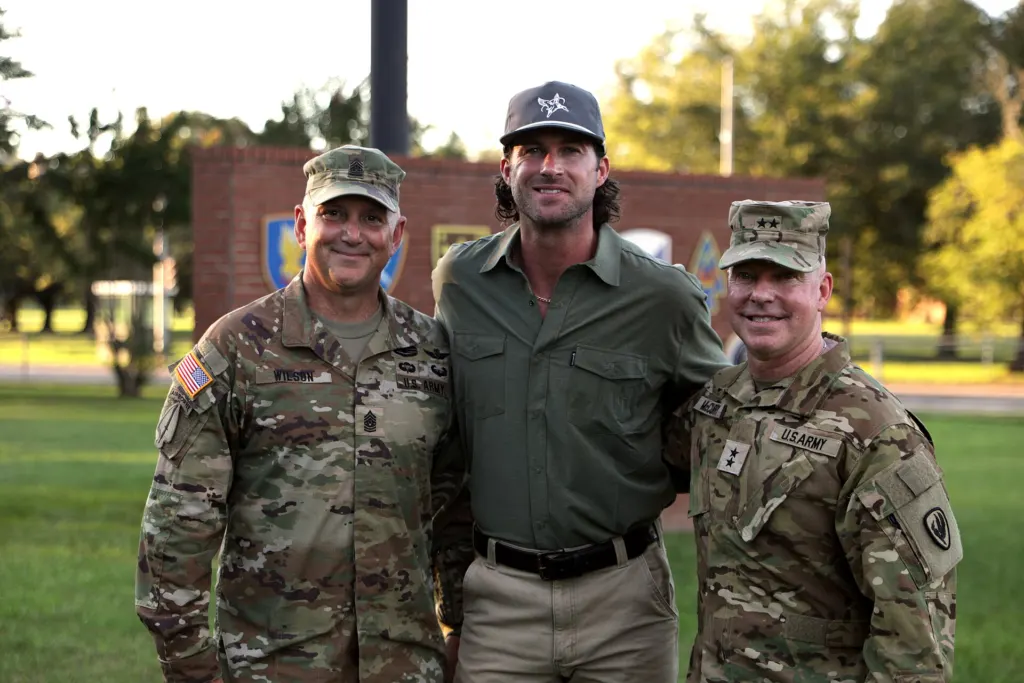 Country singer Riley Green standing with two US Army leaders during a visit to Fort Rucker, Alabama, in August 2022