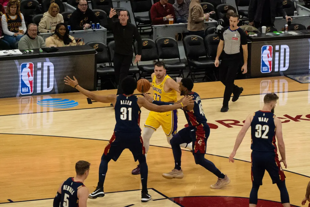 Luka Dončić in a Lakers uniform drives as Cleveland Cavaliers players Jarrett Allen and Donovan Mitchell defend during a January 2026 game